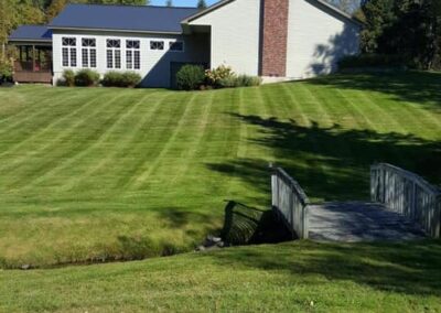 Residential yard with bridge over stream and freshly mowed lawn
